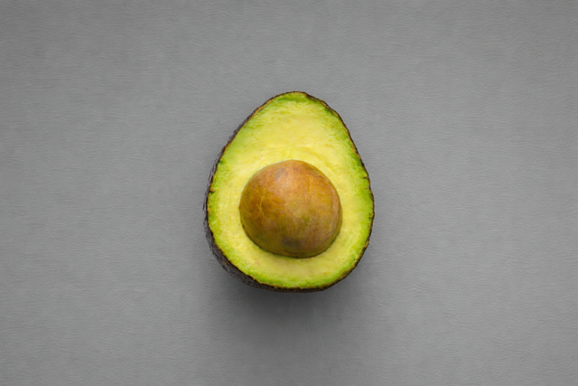An avocado on a grey background added with AI