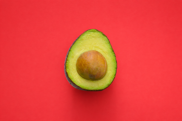 An avocado on a crimson red background added with AI