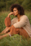 Woman sitting in a field of tall grass, surrounded by trees in the background — sample image to enhance