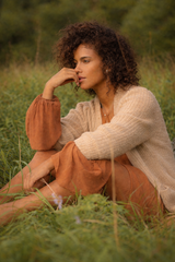 Woman sitting in a field of tall grass, surrounded by trees in the background — sample image to enhance