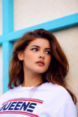 Woman wearing a white t-shirt with the word "Queens" printed on it — sample image to enhance