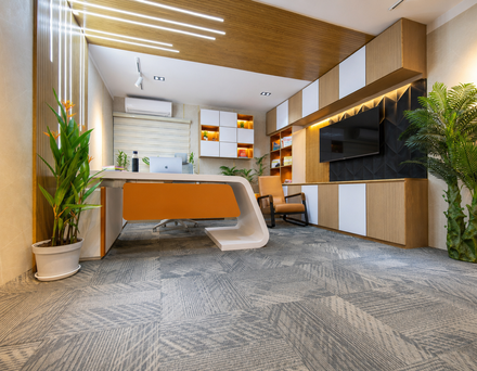 A modern office with a large desk, chairs, and houseplants, viewed from a ground-level angle.