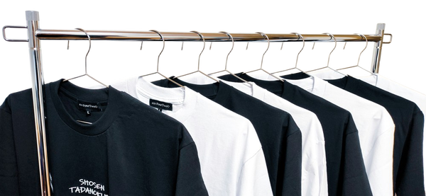 A rail of black and white t-shirts on wire hangers — background removed by Erase.bg