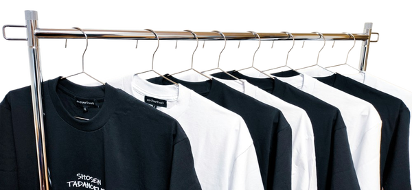 A rail of black and white t-shirts on wire hangers — background removed by Photoroom
