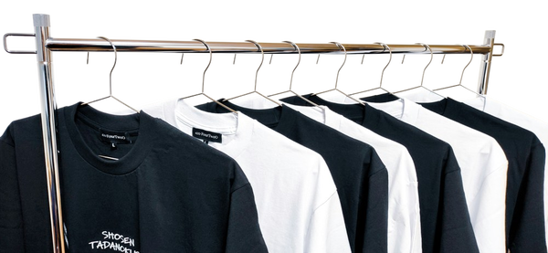 A rail of black and white t-shirts on wire hangers — background removed by Remove.bg