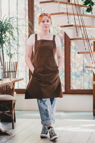 A woman in a brown apron standing in a bright cafe