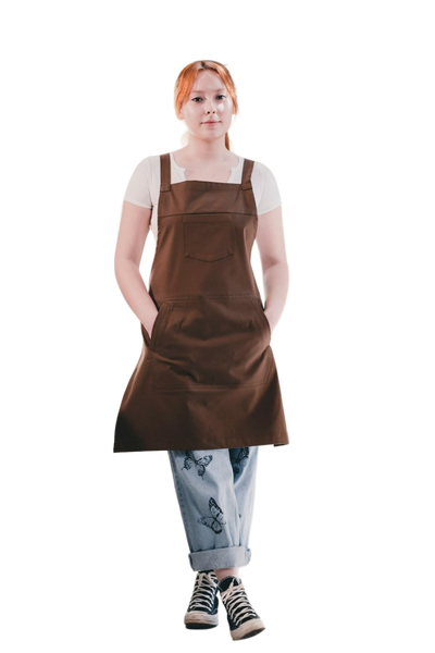 A woman in a brown apron standing in a bright cafe — background removed by Remove.bg