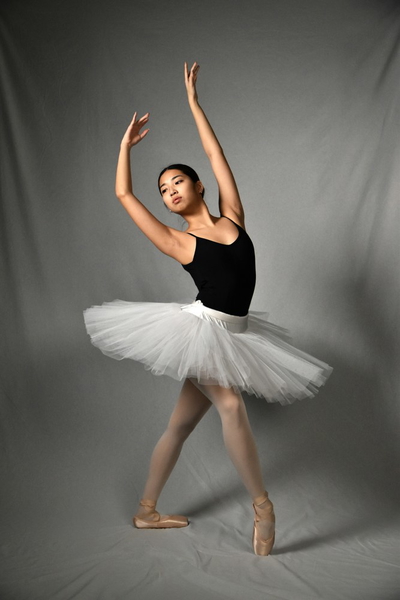 A ballerina in a white tutu, arms raised