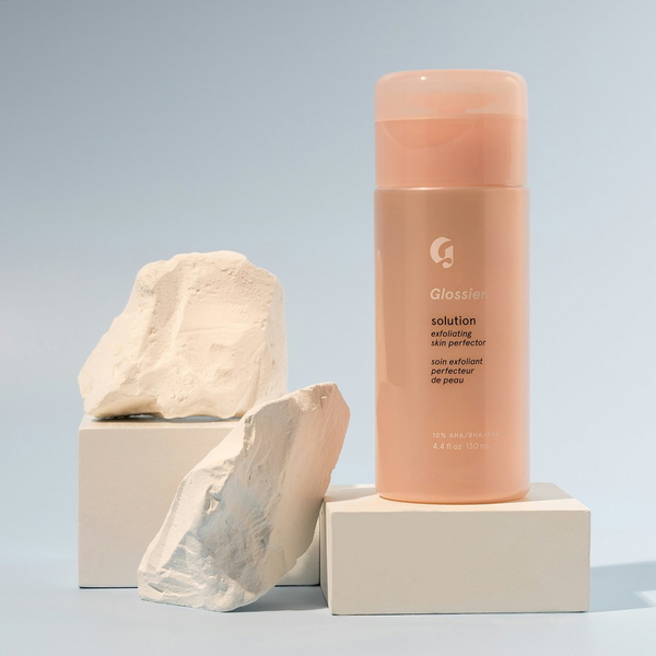 A pink cosmetic bottle balanced on a stone plinth