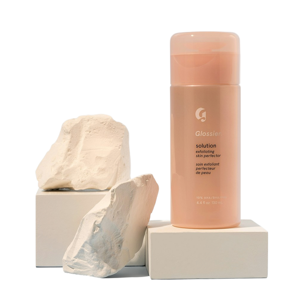 A pink cosmetic bottle balanced on a stone plinth — background removed by Remove.bg