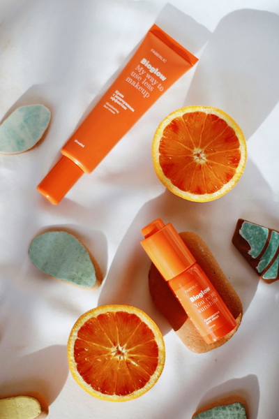 Orange skincare tubes scattered with blood orange slices