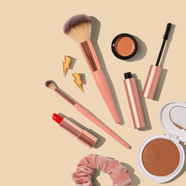 Make-up brushes, lipsticks and compacts on a beige background