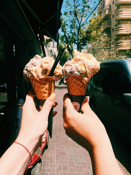 Two hands holding ice cream cones together