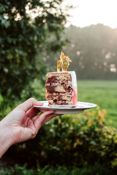 A hand holding a small cake on a plate