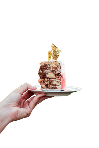 A hand holding a small cake on a plate — background removed by Photoroom