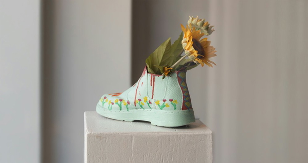Sunflowers arranged in a pale green boot-shaped vase