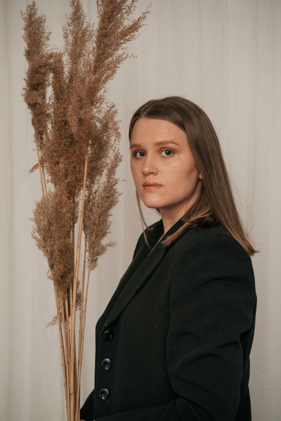 A woman in a dark blazer in front of dried pampas grass