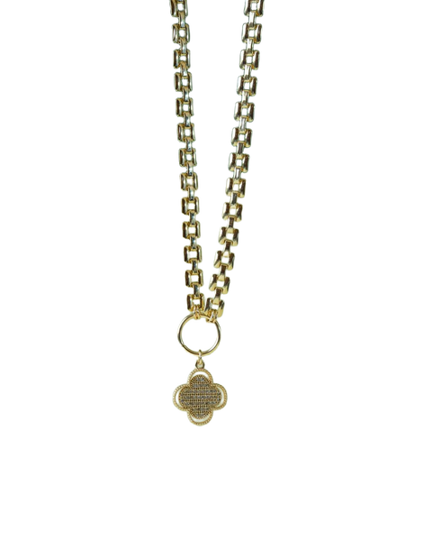 A gold chain necklace with a pendant, lying on a green leaf — background removed by Erase.bg
