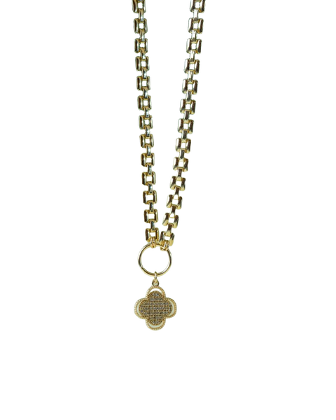 A gold chain necklace with a pendant, lying on a green leaf — background removed by Photoroom