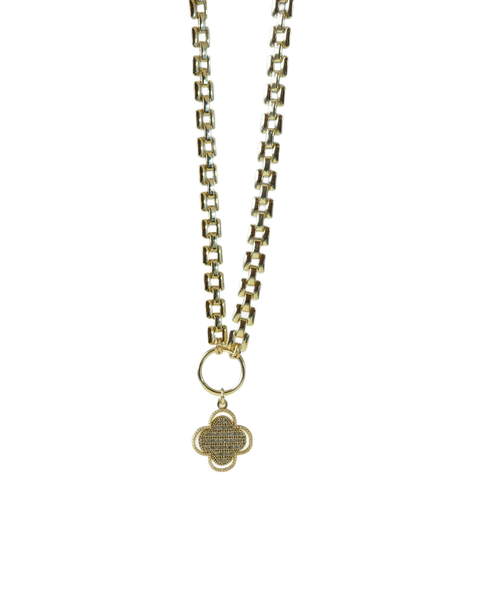 A gold chain necklace with a pendant, lying on a green leaf — background removed by Remove.bg