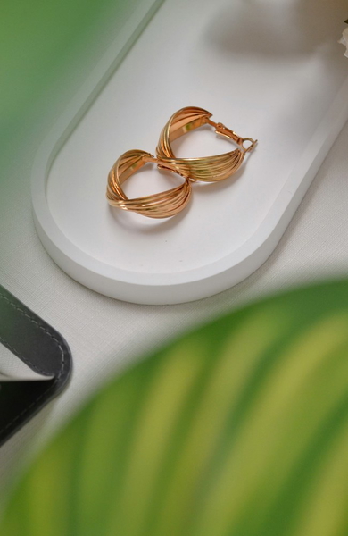 A pair of gold hoop earrings on a white tray