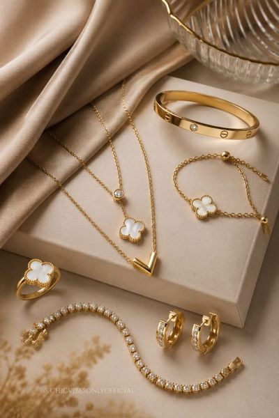 A flat-lay of gold necklaces, bangles, a ring and hoop earrings on beige satin