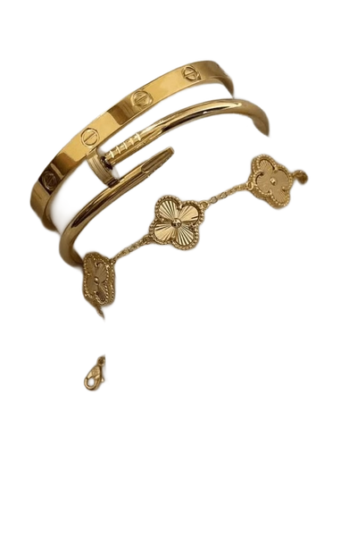 Two gold bangles and a clover-motif bracelet resting on draped white silk — background removed by Erase.bg