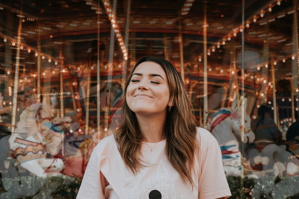 A woman laughing at a funfair, string lights behind her