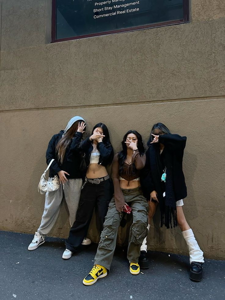 Four people in streetwear photographed against a wall
