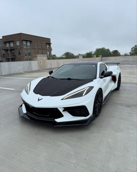 A white sports car with a carbon bonnet on a rooftop car park
