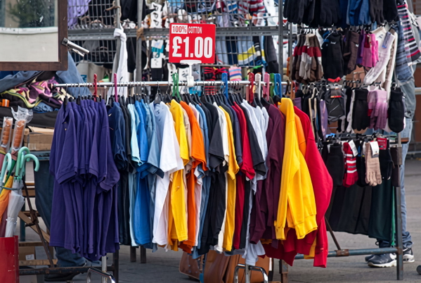 Market rail of T-shirts in bright colours under a £1.00 price sign — upscaled by GoStudio Advanced