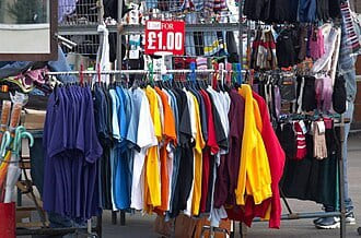 Market rail of T-shirts in bright colours under a £1.00 price sign