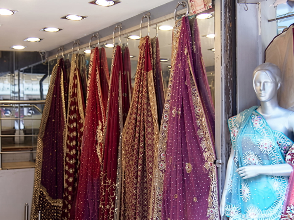 Embroidered saris hanging in a shop beside a mannequin — upscaled by GoStudio Advanced