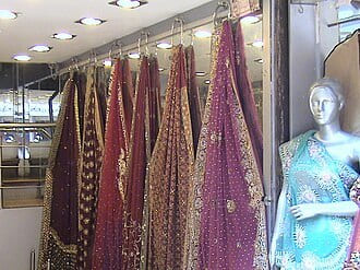 Embroidered saris hanging in a shop beside a mannequin