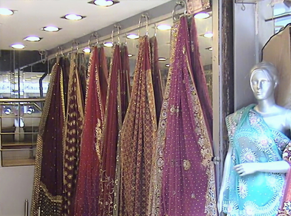 Embroidered saris hanging in a shop beside a mannequin — upscaled by GoStudio Lite