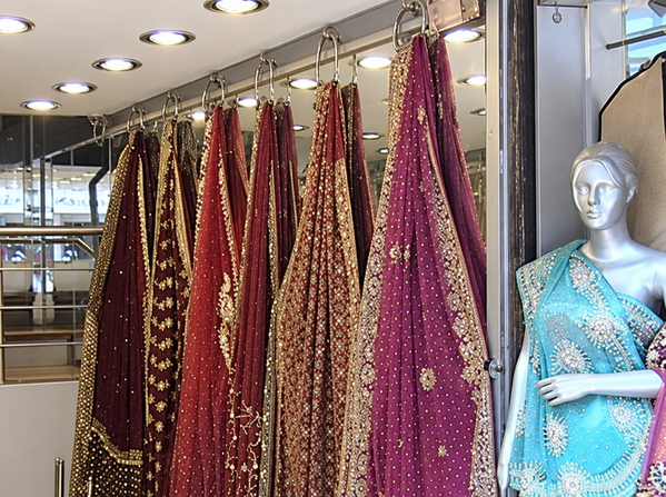Embroidered saris hanging in a shop beside a mannequin — upscaled by GPT Image 2.5