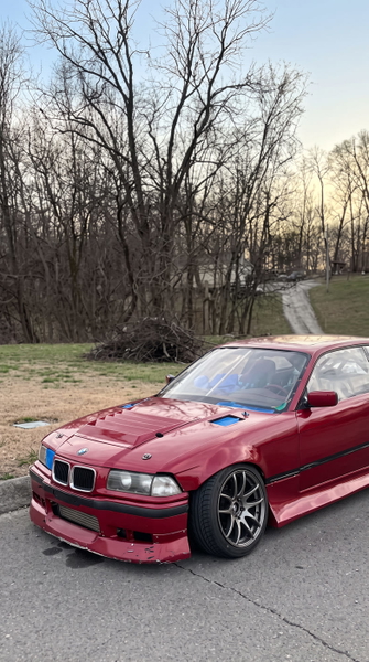 Red coupé parked on a driveway in front of bare winter trees — upscaled by GoStudio Advanced