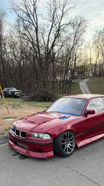 Red coupé parked on a driveway in front of bare winter trees