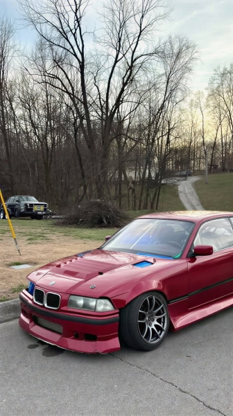 Red coupé parked on a driveway in front of bare winter trees — upscaled by GoStudio Lite