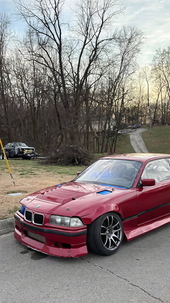 Red coupé parked on a driveway in front of bare winter trees — upscaled by GoStudio Pro
