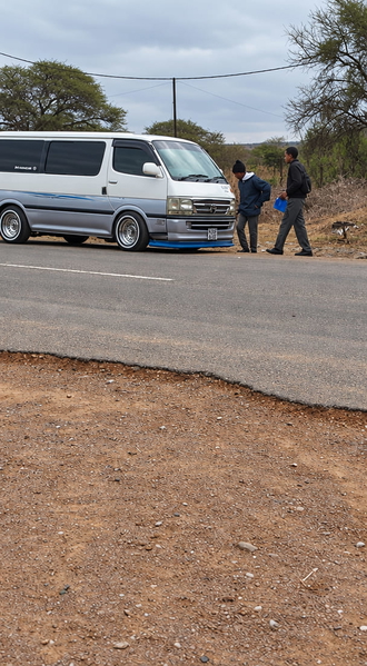 White van on a dirt road with two people standing beside it — upscaled by GPT Image 2.5