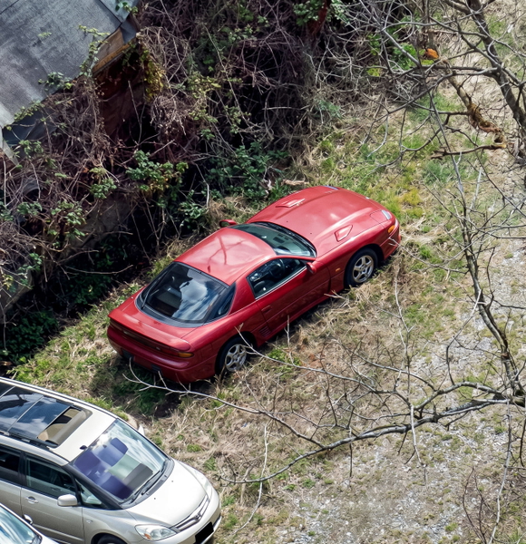 Aerial view of a red car on grass beside a road — upscaled by Nano Banana 2
