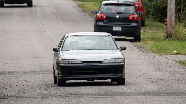 White hatchback on a suburban road, from a 1280×720 video still — upscaled by GoStudio Advanced