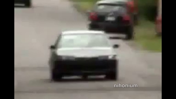 White hatchback on a suburban road, from a 1280×720 video still