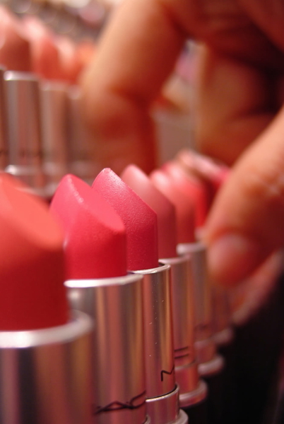 Row of pink and red lipsticks with a hand reaching in, shallow depth of field — upscaled by GoStudio Advanced