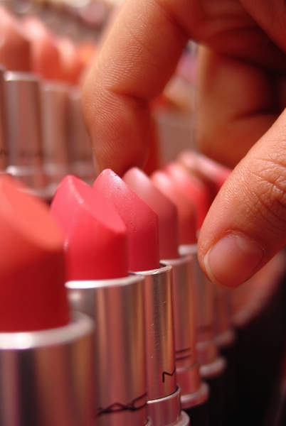Row of pink and red lipsticks with a hand reaching in, shallow depth of field — upscaled by Nano Banana 2