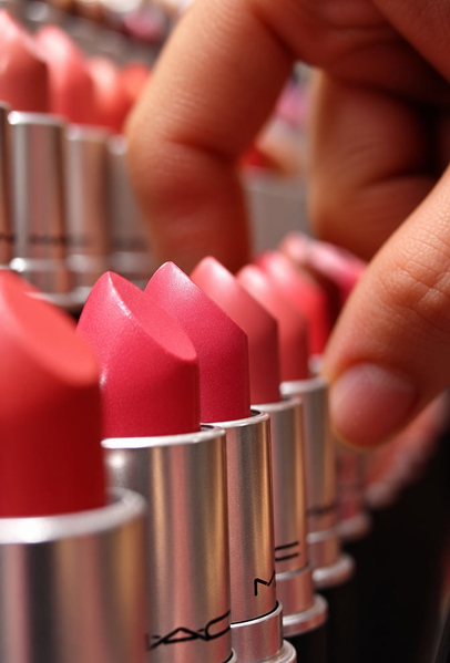 Row of pink and red lipsticks with a hand reaching in, shallow depth of field — upscaled by GPT Image 2.5