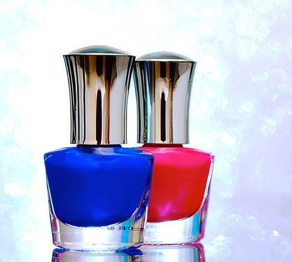 Two nail-polish bottles, blue and pink, with silver caps against a sparkling background — upscaled by GoStudio Pro