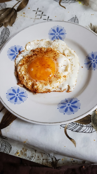 Fried egg on a white plate with a blue floral pattern — upscaled by GoStudio Advanced