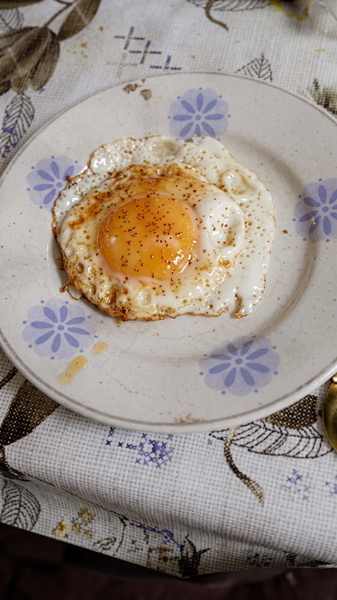 Fried egg on a white plate with a blue floral pattern — upscaled by Nano Banana 2